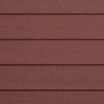 Close-up of a red wooden siding wall with horizontal planks. The texture of the wood grain is visible, giving the surface a rustic appearance. The planks are evenly spaced and overlap each other.