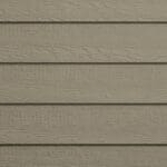 Close-up of beige horizontal wooden siding with a textured, wood grain pattern. The panels are evenly spaced, giving a neat and uniform appearance typical of exterior house cladding.