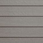 Close-up of beige horizontal wooden siding with a textured, wood grain pattern and subtle shadows between the overlapping boards.