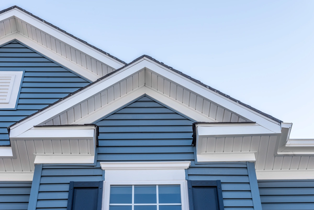 Blue vinyl siding with white trim and gable details on a residential home