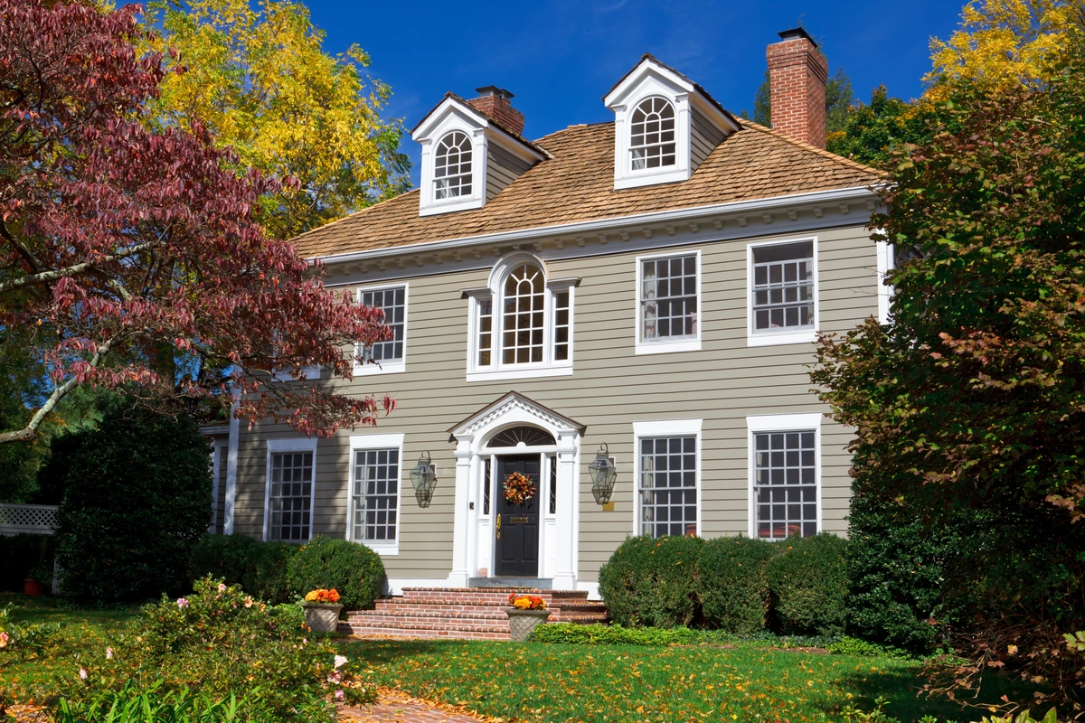 Colonial-style home with new light grey vinyl siding, white trim, and cedar shake roof