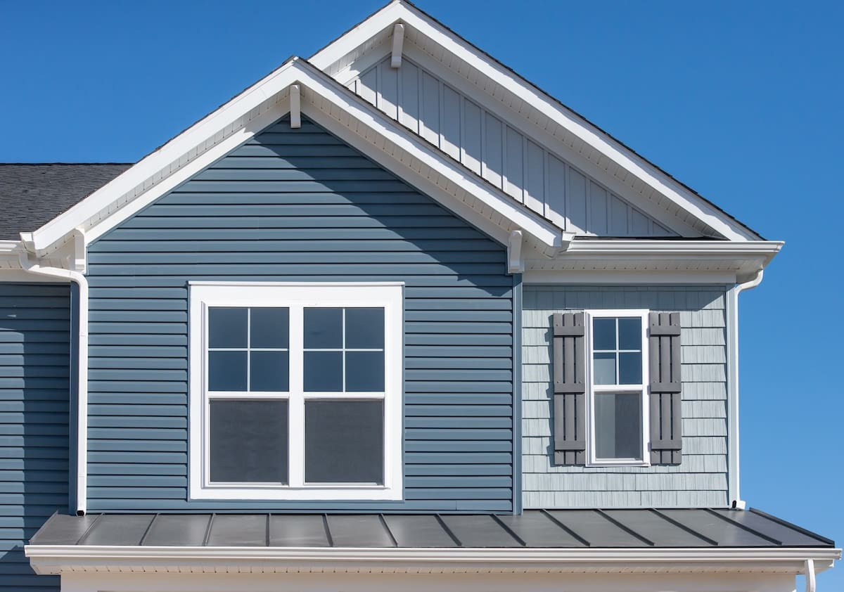 A modern house exterior with blue vinyl shake siding and white trim