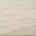 Light-colored wooden surface with subtle grain patterns and faint natural lines running horizontally across the image. The texture appears smooth and evenly finished.