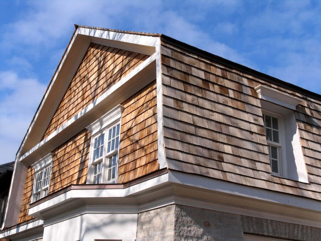 A close-up view of a house with cedar siding on the upper floor