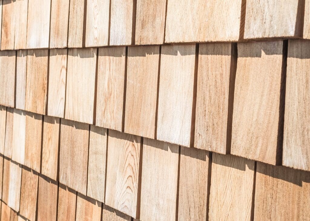 Close-up of a wall covered with overlapping light brown wooden shingles