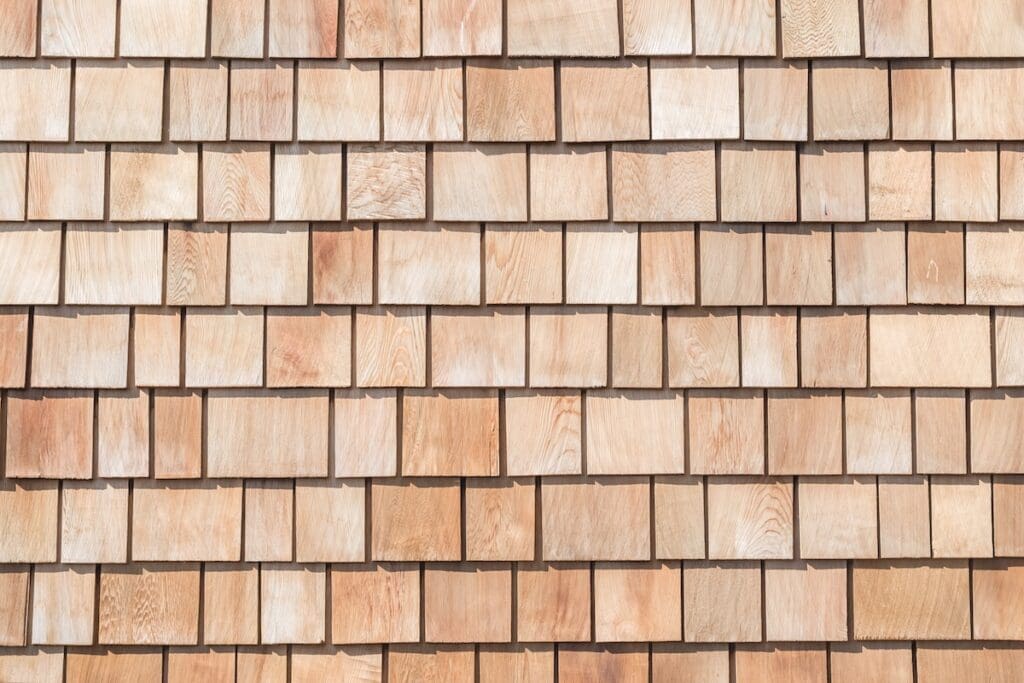 Close-up of a wall covered in evenly arranged, overlapping cedar siding shingles.
