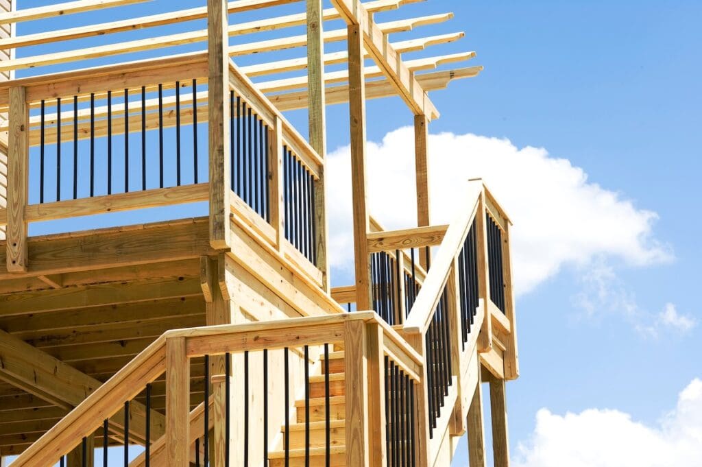 Wooden outdoor multi level deck and staircase with black metal railings