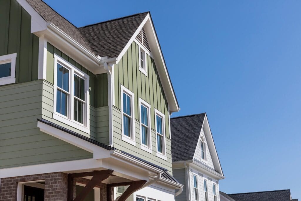 Close-up view of a modern suburban house with sage green siding and white trim