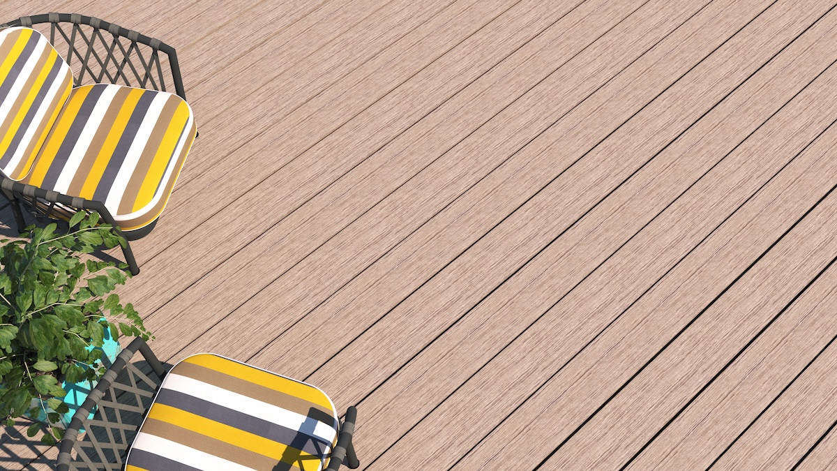 Two black metal chairs with yellow, white, and gray striped cushions sit on a light wood deck, partially visible in the top left corner. A leafy green plant is nearby. The rest of the deck is empty, showing how to clean Trex decking easily.