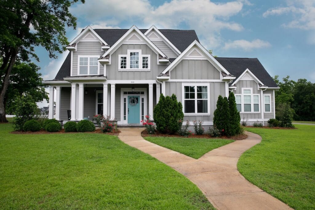 A modern two-story gray house with lp smartside siding colors, white trim, large windows, a covered front porch, and a blue front door.