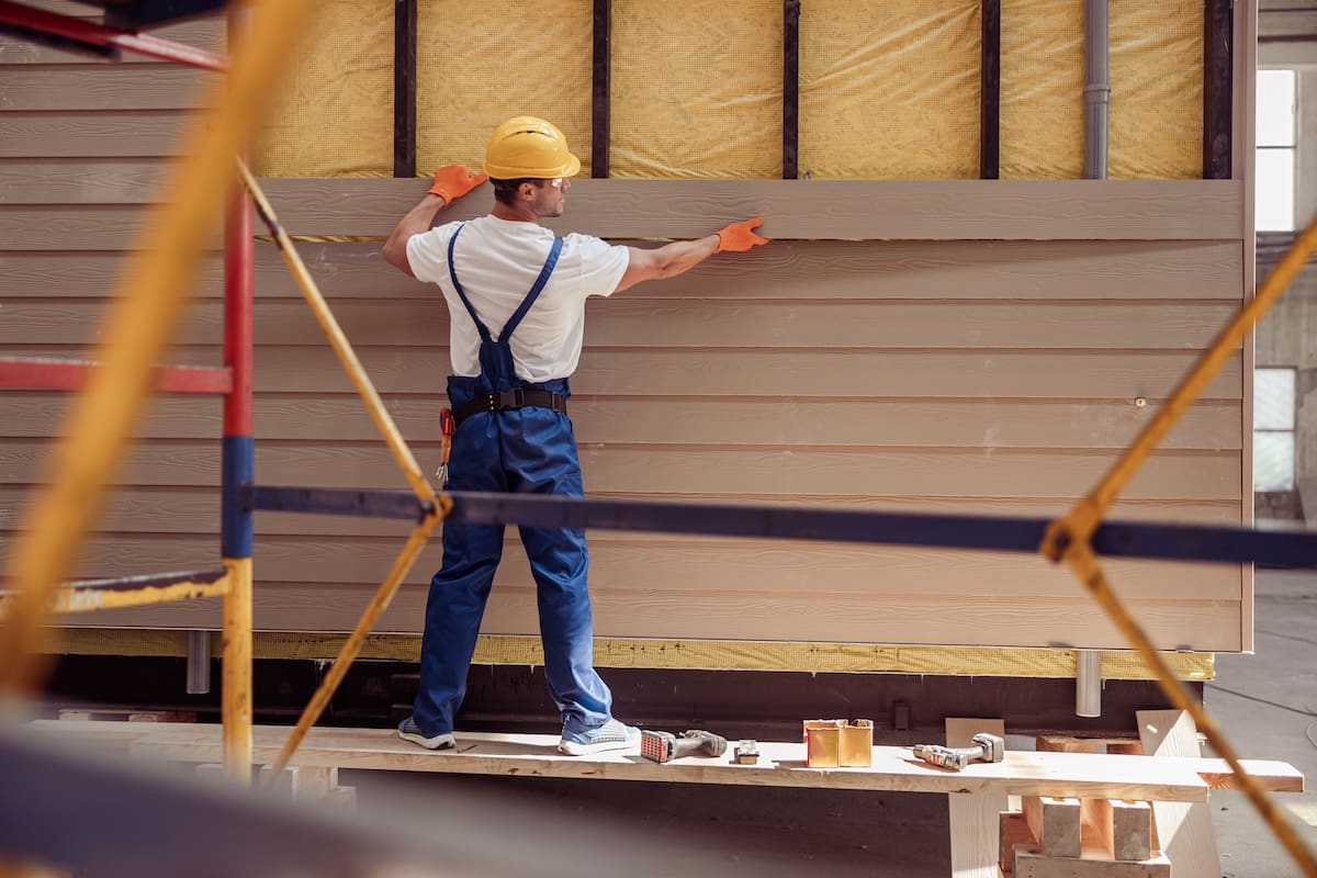 Contractor installing horizontal vinyl siding panels on a residential home exterior