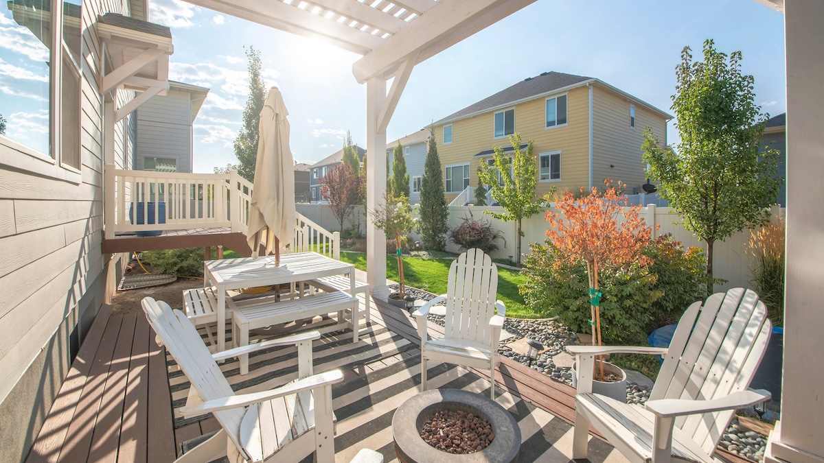 Pano Backyard of a house with a pergola covered patio beside the small door deck.
