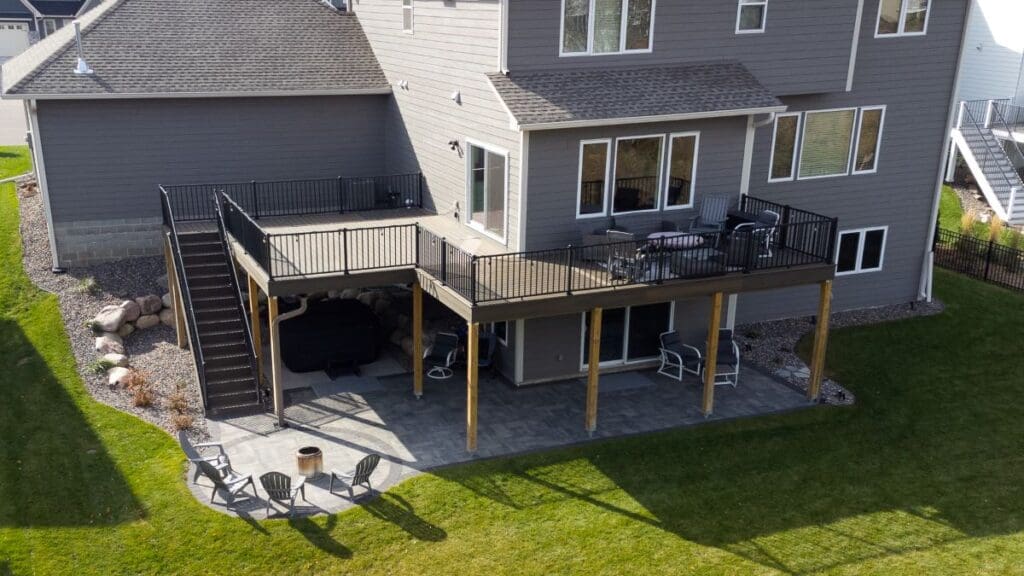 A two-story gray house features an elevated deck with black railings