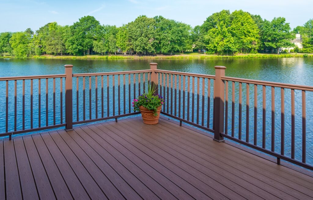 A wooden deck with brown railings overlooks a calm lake