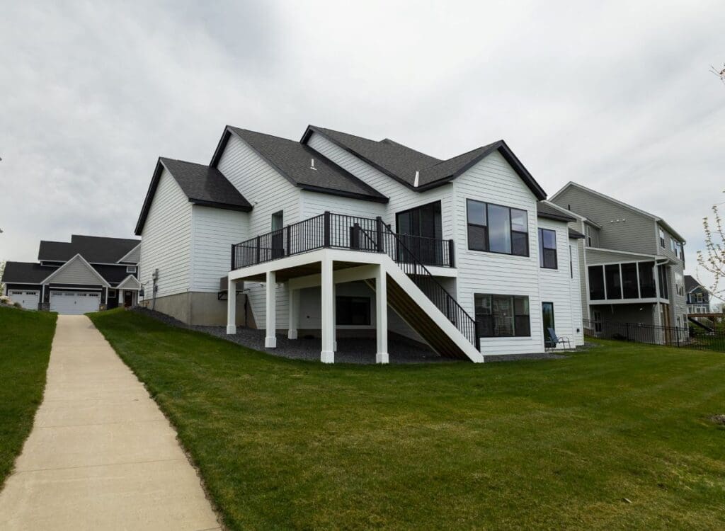 A modern two-story white house with an elevated deck featuring sleek Westbury railing