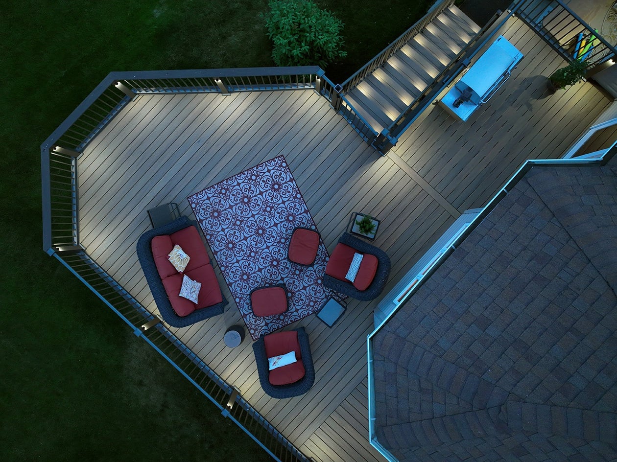 Aerial view of a well-lit outdoor deck at dusk, featuring integrated deck lighting complete this inviting Twin Cities retreat.