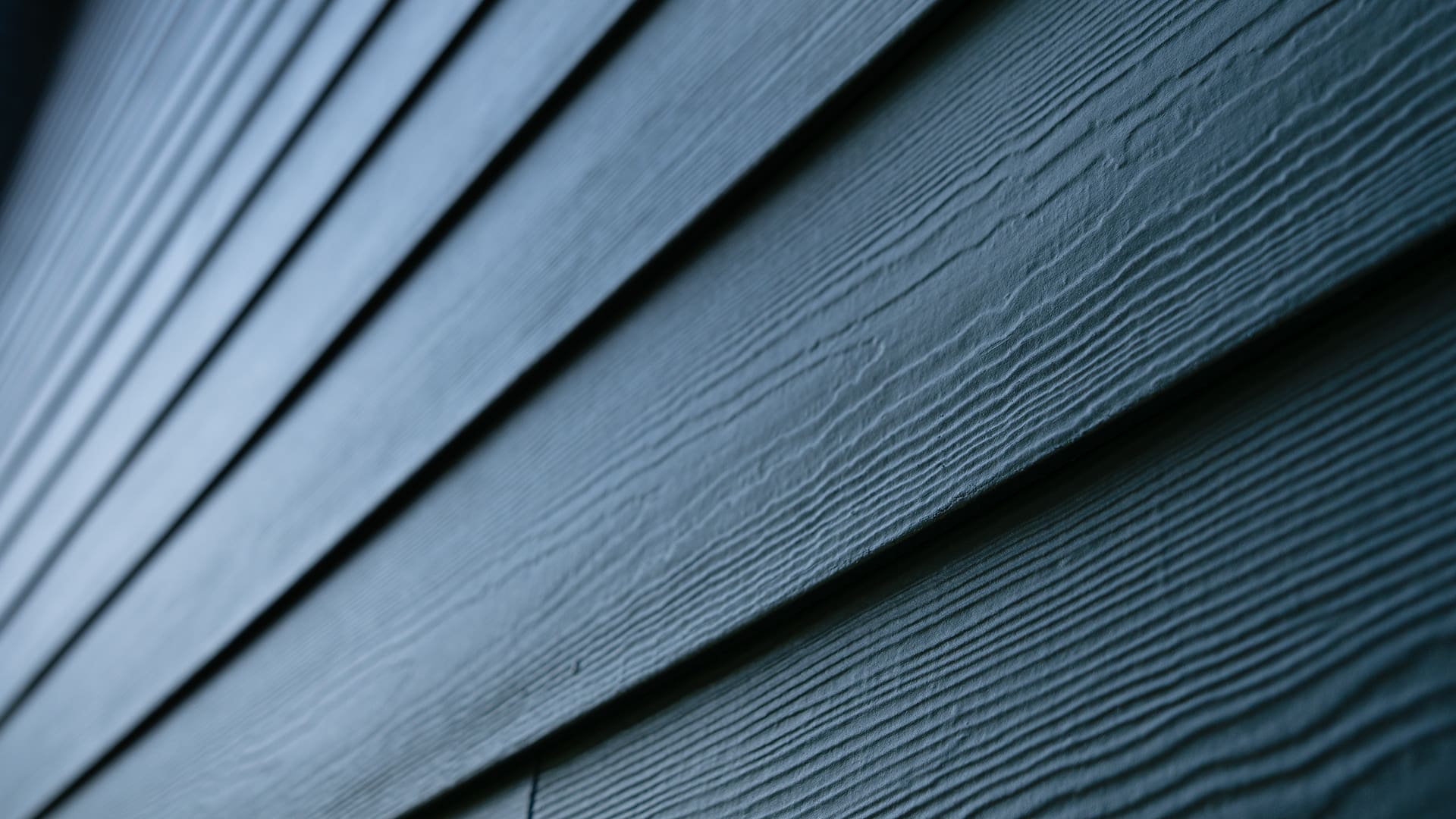 Close-up view of horizontal dark blue siding panels on a building, showing textured lines and a pattern of overlapping boards—ideal for pairing with a TimberTech White Oak deck or James Hardie Mountain Sage accents.